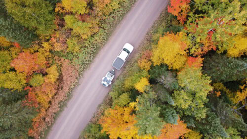 Vistabule Towed By Vehicle Drone View Of Vistabule Beong Towed Through Fall Trees